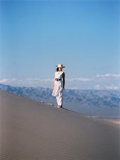 a woman standing on top of a sand dune