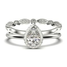 a pear shaped diamond engagement ring set on top of two wedding bands, with the band in