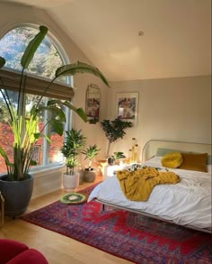 a bedroom with a large bed and lots of plants in the window sill next to it