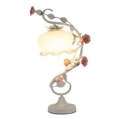 a lamp that is on top of a stand with flowers and leaves around it's base