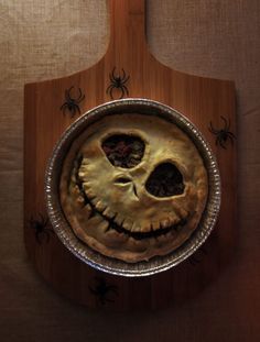 a wooden cutting board with a pie in the shape of a jack skellingy face