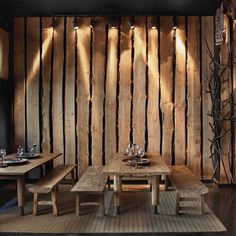 a wooden table and benches in a room with wood paneling on the wall behind it