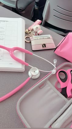 pink scissors and other items are sitting on a table next to an open medical bag