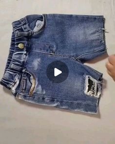 someone is holding up an old pair of jeans with holes in it and the bottom part has been torn off