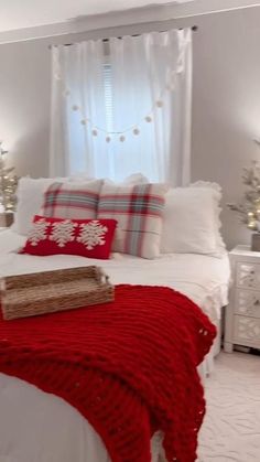 a white bed topped with pillows and blankets next to a window covered in christmas lights