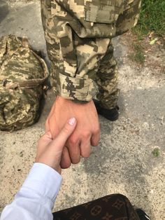 two people holding hands while standing next to each other in front of a bag and backpack