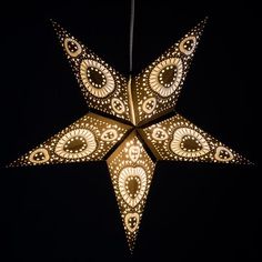 a star shaped light hanging from the ceiling with intricate designs on it's sides