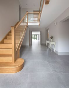 an empty hallway with stairs and table in the middle is seen from across the room