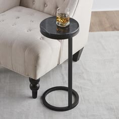 a chair with a glass on it next to a small end table in front of a couch