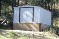 a white shed sitting in the middle of a forest