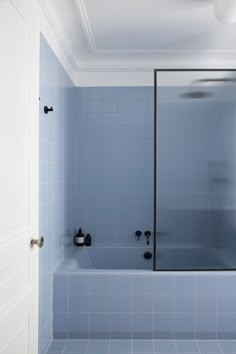 a blue tiled bathroom with a shower and bathtub