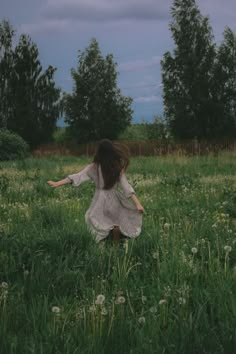 a woman in a field with her arms spread out to the side as she walks through tall grass