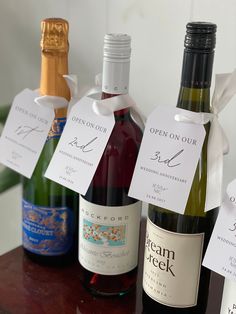 several bottles of wine are lined up on a table with white tags attached to them