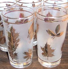 four glasses with leaves on them sitting on a table