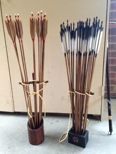 two vases with arrows in them sitting next to each other on the floor near a wall