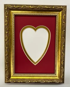 a red and gold frame with a white heart cut out in the middle on a wall