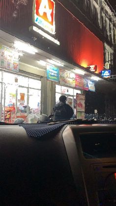 a person sitting in the passenger seat of a car at night with neon signs above