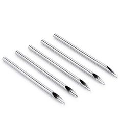 four different sized metal pens on a white surface with one pen pointed at the top