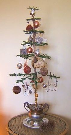 a small christmas tree on top of a round table with ornaments hanging from it's branches