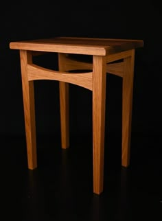 a small wooden table sitting on top of a black floor