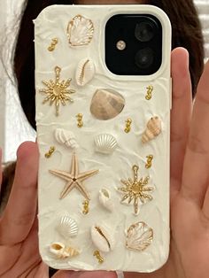 a person holding up a phone case with shells and starfishs on it