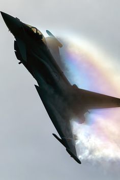 a jet flying through the air with a rainbow in the background