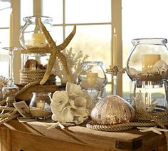 a table topped with lots of glass vases filled with flowers and seashells