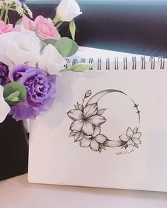 a drawing of a crescent with flowers in front of it on a desk next to a notepad