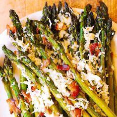 asparagus with bacon and parmesan cheese on top, served on a white plate