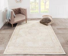 a white rug with an ornate design on the floor next to a chair and ottoman