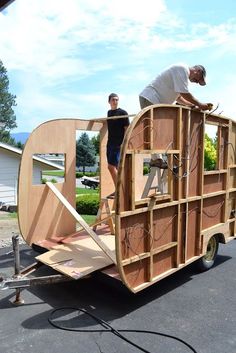 two men are working on a trailer made out of plywood and wooden planks