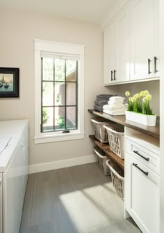 a laundry room with white cabinets and drawers