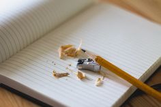 an open notebook with a pencil and eraser on it, next to some burnt pieces of paper