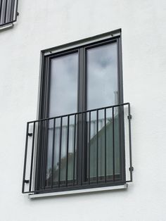 an open window on the side of a white building with black metal bars and balconies