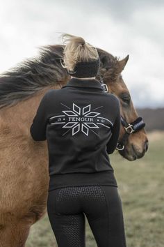 a woman standing next to a brown horse