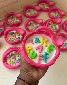 a hand is holding a pink toy with letters on it