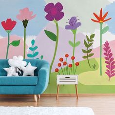 a living room with colorful flowers painted on the wall and a blue chair in front