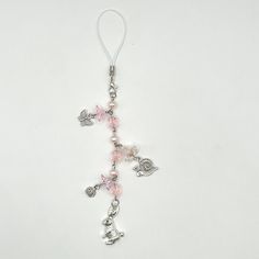 a rosary with pink beads and silver charms on a white background, the cross is decorated with hearts