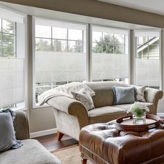 a living room filled with furniture and windows covered in blind shades on the windowsill