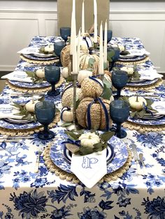 a blue and white table setting with pumpkins, candlesticks and other decorations