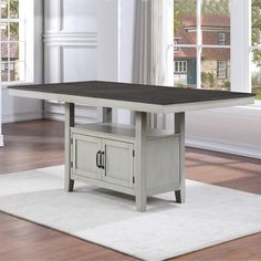 a dining room table with two cupboards on each side and a rug underneath it