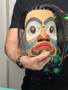 a man is holding a mask in front of his face