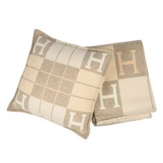 two brown and white pillows sitting on top of each other with the letter h on them