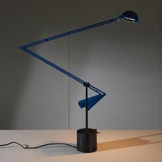 a blue desk lamp sitting on top of a white table next to a light bulb