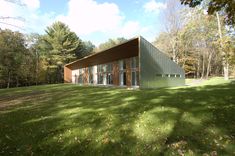 a green house sitting on top of a lush green field next to trees and grass