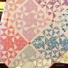 a colorful quilt is displayed on a wooden table in front of some grass and trees