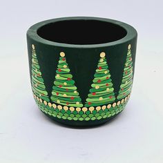 a green pot with christmas trees painted on it