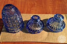 three blue glass jars sitting on top of a wooden table next to a brown napkin