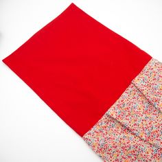 a red piece of cloth sitting on top of a white table next to a pair of scissors