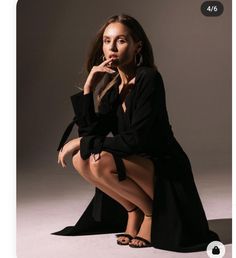 a woman is sitting on the ground posing for a photo with her hand under her chin